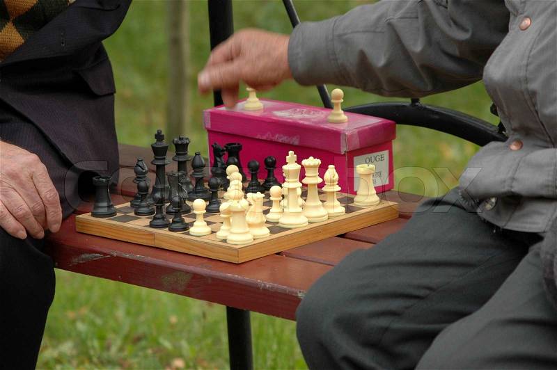 Two old men playing chess in a park, stock photo