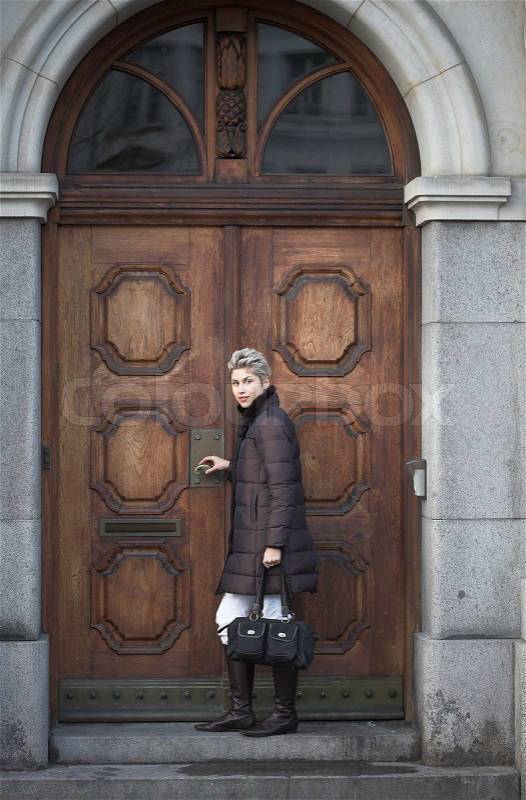 Woman outdoor in a city on shopping tour looking at the camera a house door, stock photo