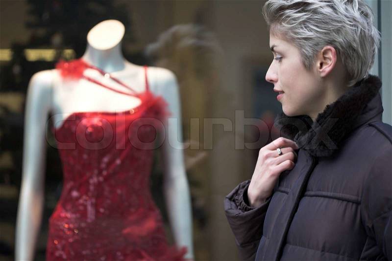 Woman outdoor in a city on shopping tour, looking into a shop window, stock photo