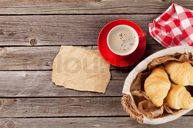 Fresh croissants and coffee on wooden table. Top view with paper for your note, stock photo