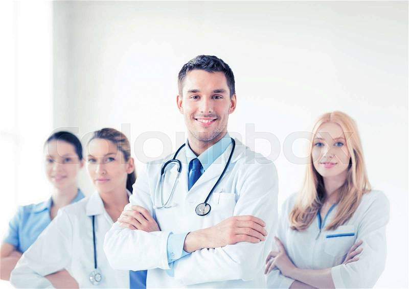 Attractive male doctor in front of medical group, stock photo
