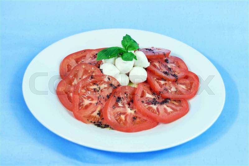 Modern food on a white plate and blue background - tomatoes with mozzarella and basil - caprese salad, stock photo