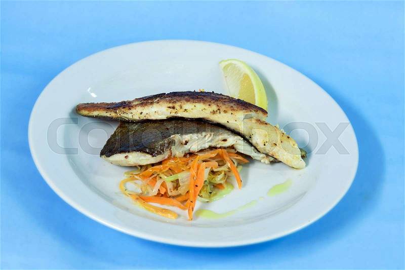 Modern food on a white plate and blue background - grilled boneless trout with roasted vegetables, stock photo