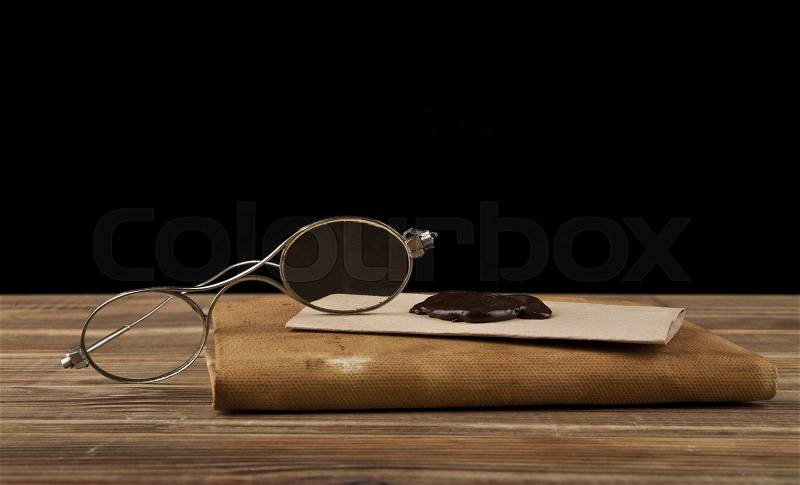 Old glasses and old books on black background, stock photo