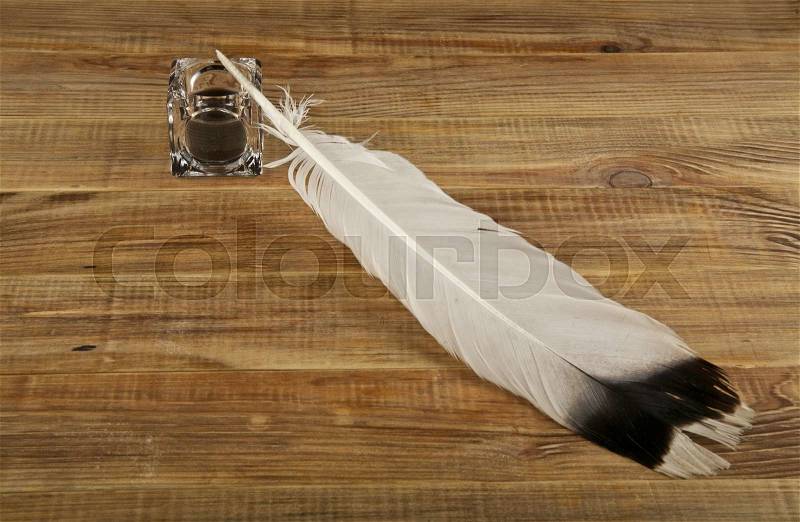 Pen and inkwell on wooden background, stock photo
