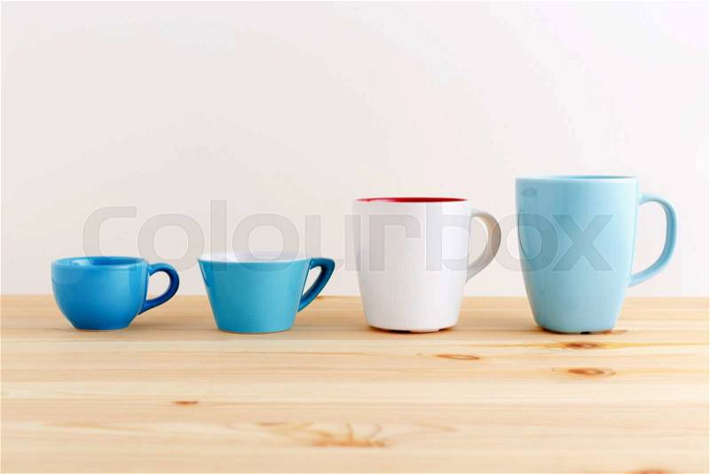 Mugs and cups in blue and white on wood table, stock photo