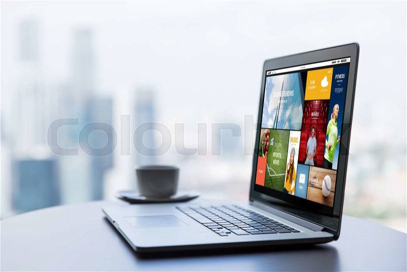 Technology, internet, media, business and modern life concept- close up of open laptop computer with news web page on screen and coffee cup on table at office or hotel room, stock photo
