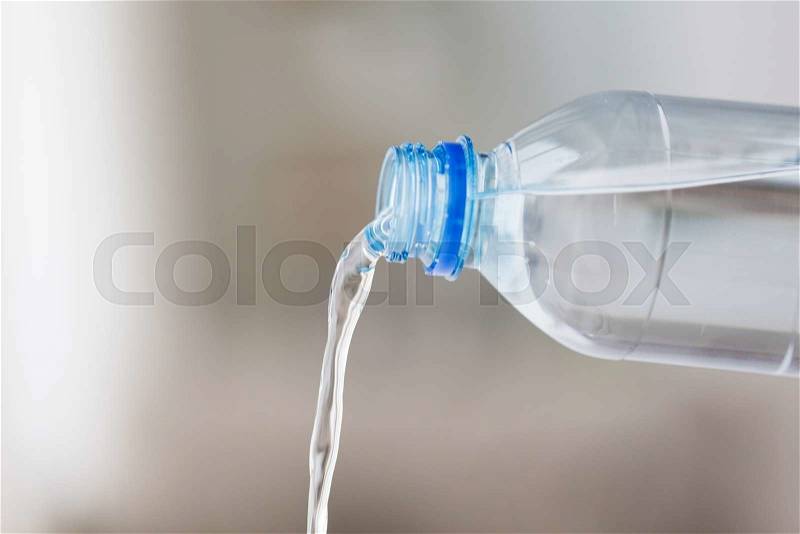Drinking, healthy eating and food storage concept - close up of water pouring from plastic bottle, stock photo