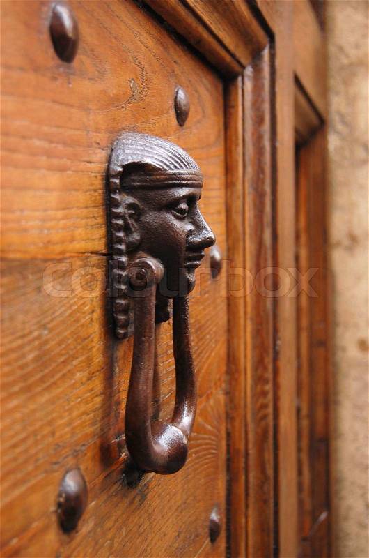 Close-up of the Egyptian human head door knocker in Rome. Bright wooden door, stock photo
