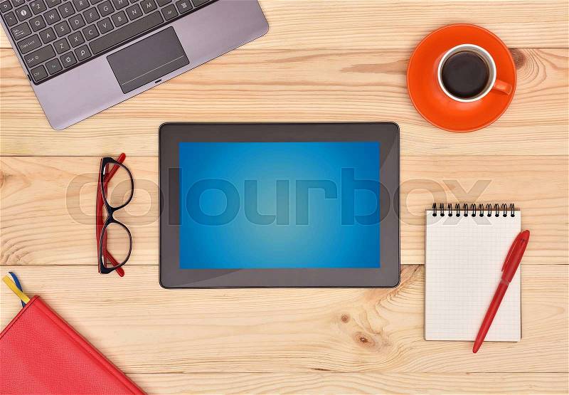 Digital Touch pad with blank screen and many business objects on wooden desk, stock photo