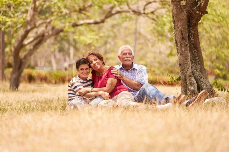 Old people, senior couple, elderly man and woman. Outdoor family having fun with happy grandpa and grandma hugging boy at picnic in park, stock photo