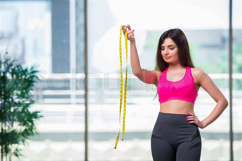 Young woman with centimeter in weight loss concept, stock photo