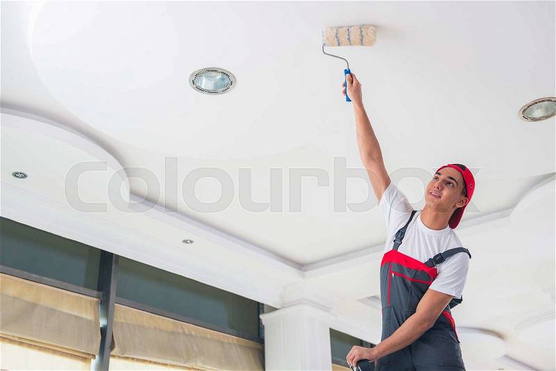 Young painter painting the ceiling in construction concept, stock photo