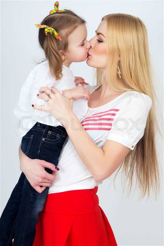 Beautiful young blonde mother kisses daughter, stock photo