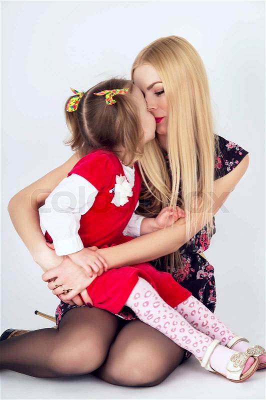 Beautiful young mother kissing daughter, stock photo