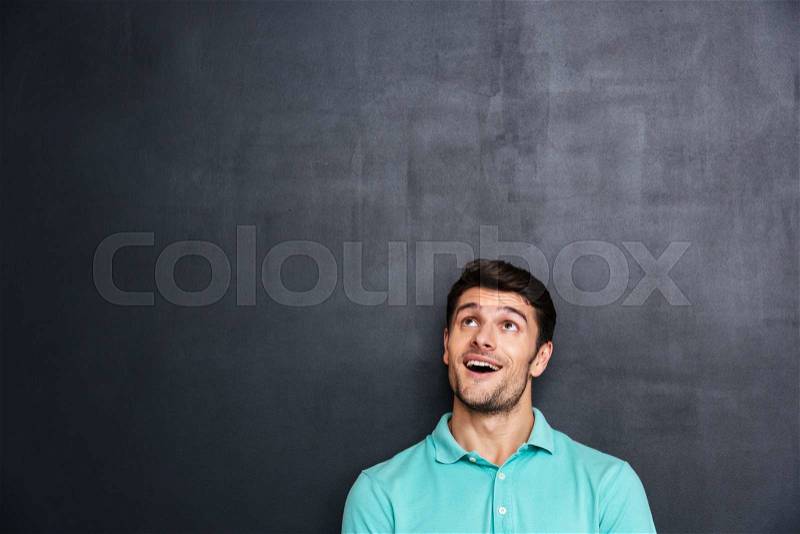 Wondered happy young man with mouth opened looking up, stock photo