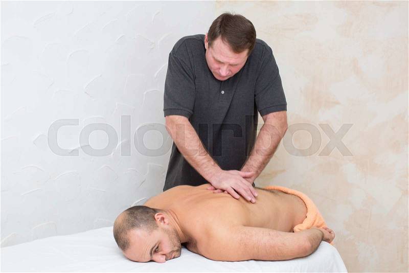 Man doing sports massage at the massage parlor, stock photo