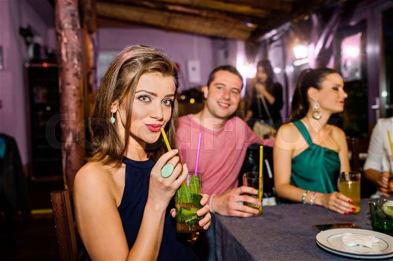 Young beautiful people with cocktails in bar or club having fun, stock photo