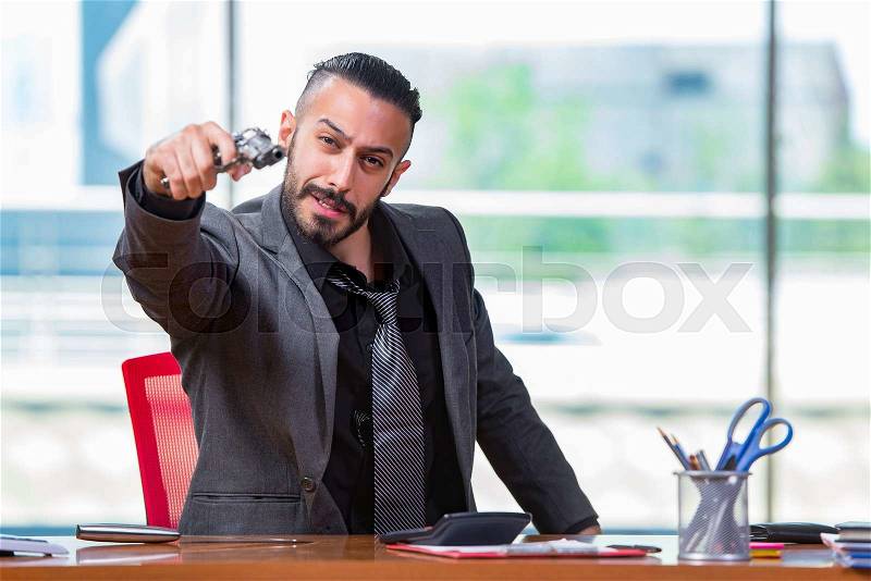 Angry aggressive businessman with gun in the office, stock photo