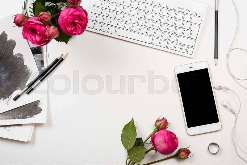 Modern smartphone, computer keyboard and fesh pink flowers on white table, freelancer blogger workspace, screen mockup, stock photo