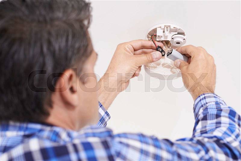 Man Replacing Battery In Home Smoke Alarm, stock photo
