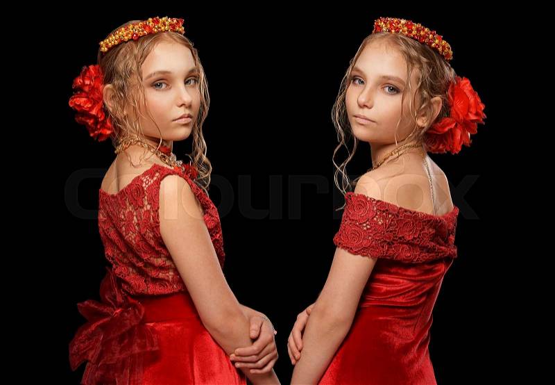 Portrait of beautiful little girls in red dresses on black background, stock photo