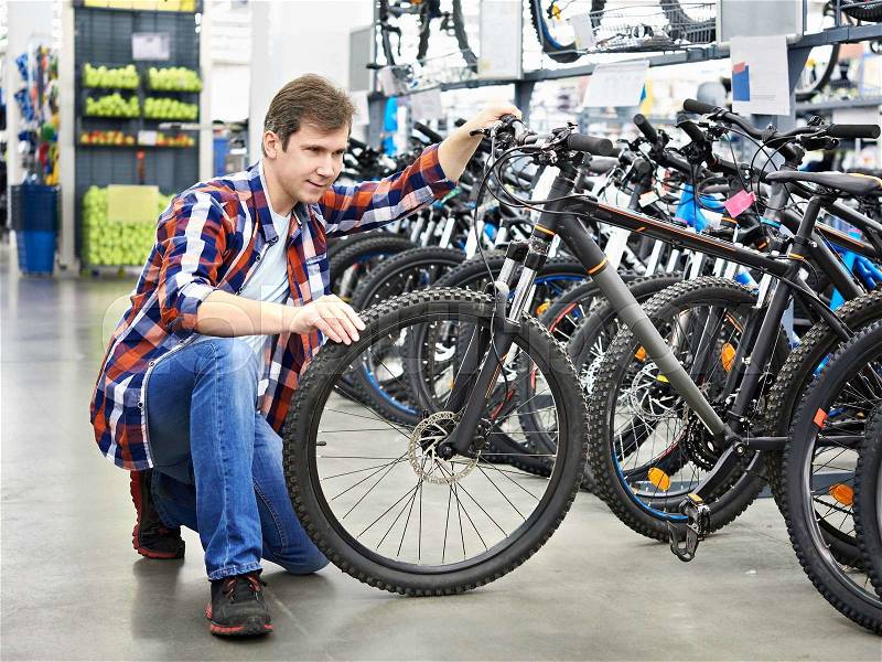 Man checks bike before buying in sports shop, stock photo