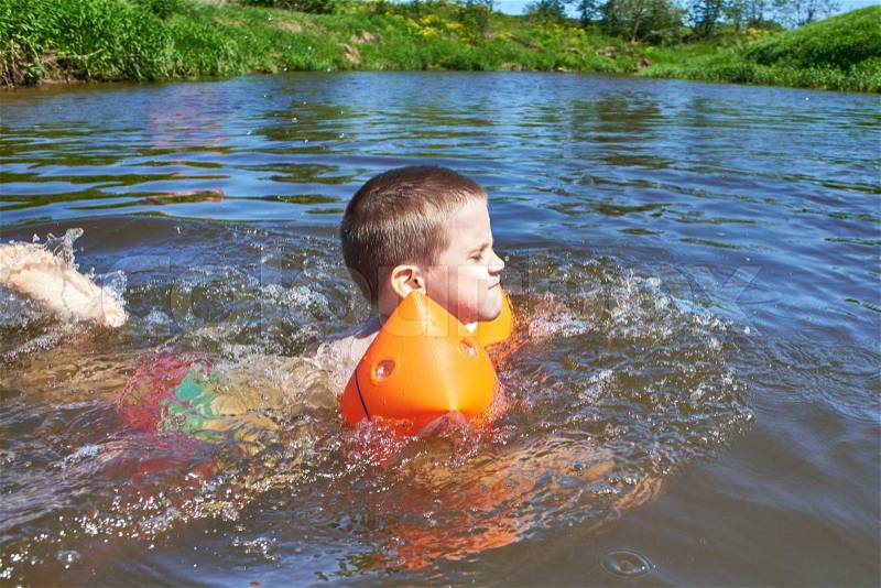 Little boy swimming in river on summer day, stock photo