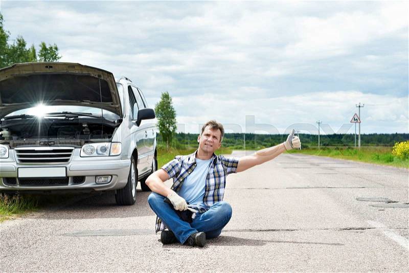 Man with tools waiting to help and showing thumbs up near his broken car, stock photo