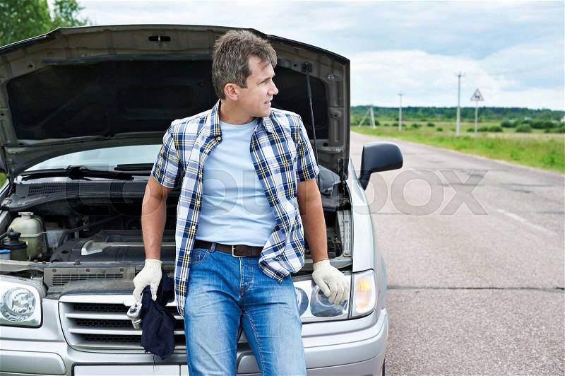 Man with tools waiting to help near his broken car, stock photo