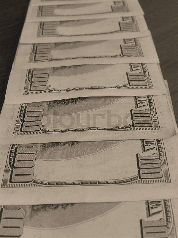 On a photo denominations of 100 dollars a line are laid out. Denominations lay on a table. A photo in brown tones. The photo is made in Ukraine, stock photo