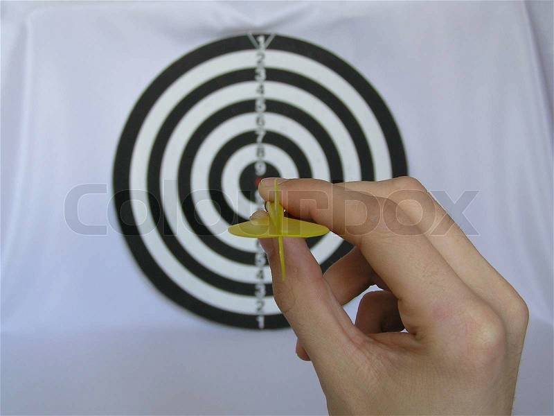 On a photo game in a darts. It black a white target. In the foreground a hand holding a dart ready to throw in a target. The photo is made in Ukraine in the city of Dubno, stock photo