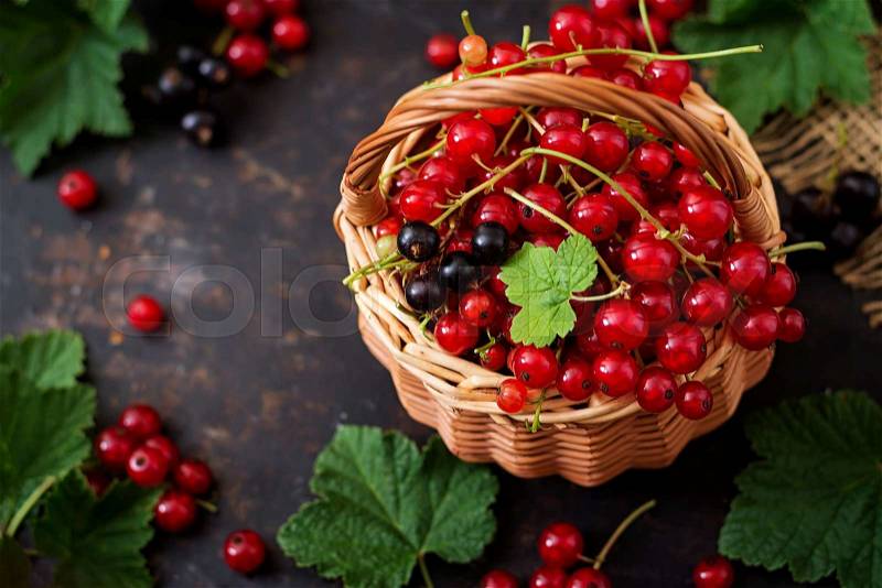 Basket with Red and Black currant with leaves on a black background, stock photo