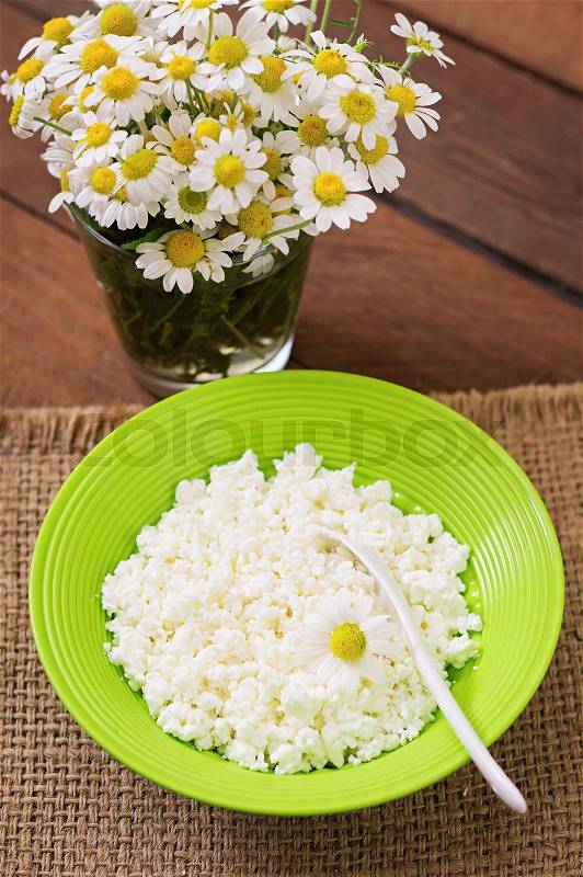 Cottage cheese for breakfast in green bowl on wooden background. Close up, stock photo