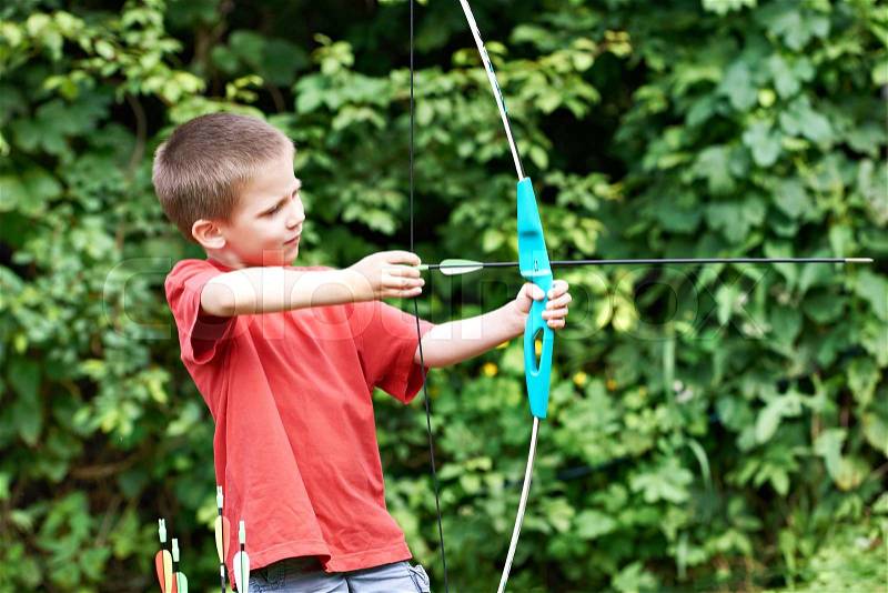 Little archer with bow and arrows outdoors, stock photo