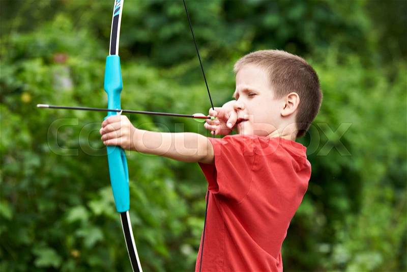 Little archer with bow and arrow outdoors, stock photo