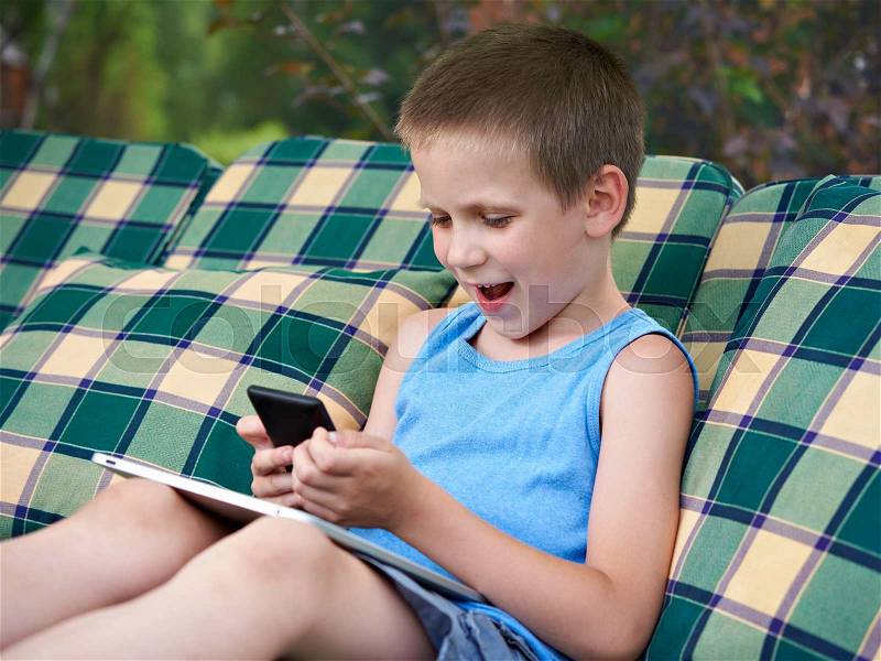Little boy with smart phone and tablet pc in summer day, stock photo