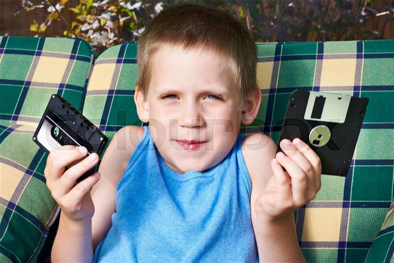 Little boy with floppy disk and audio cassette in summer day, stock photo