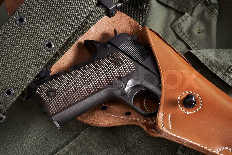 Colt pistol in a holster and belt lie on military jacket closeup, stock photo