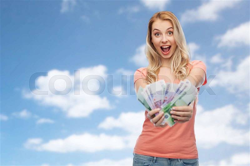 Money, finances, investment, saving and people concept - happy young woman with euro cash money over blue sky and clouds background, stock photo
