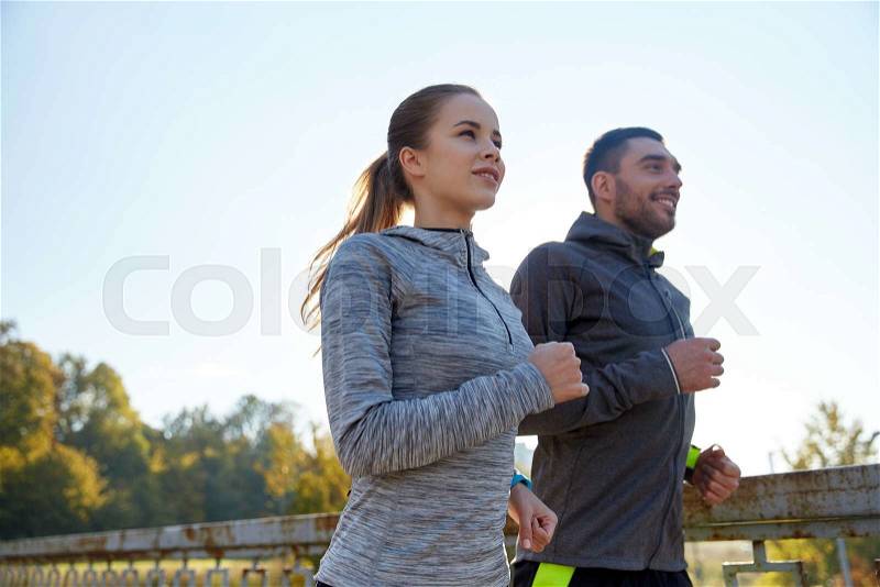 Fitness, sport, people and jogging concept - happy couple running outdoors, stock photo