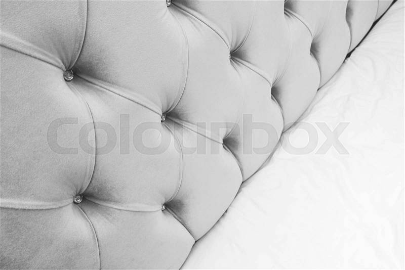 Luxury empty bedroom interior fragment, soft gray headboard and white bedding sheets on wide double bed, stock photo