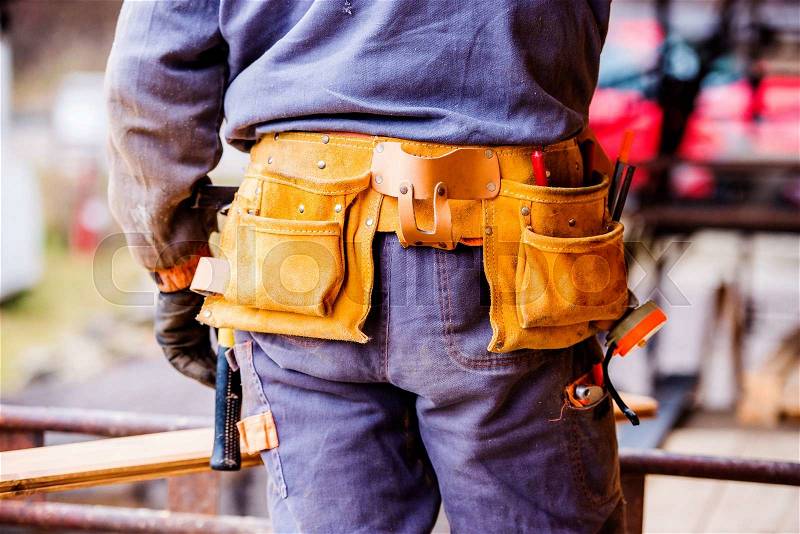 Close up of unrecognizable construction worker with tool bag on site, rear view, stock photo