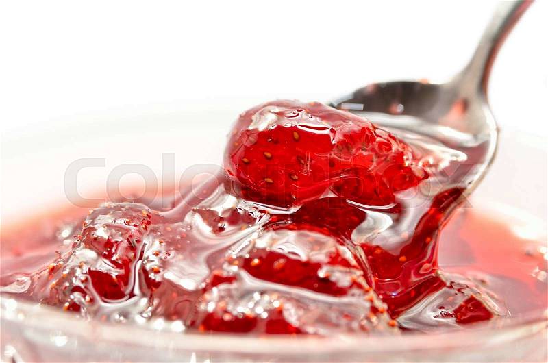 Strawberry jam is stirred with a spoon on a white background. Fruit dessert close up. Confectionery, stock photo