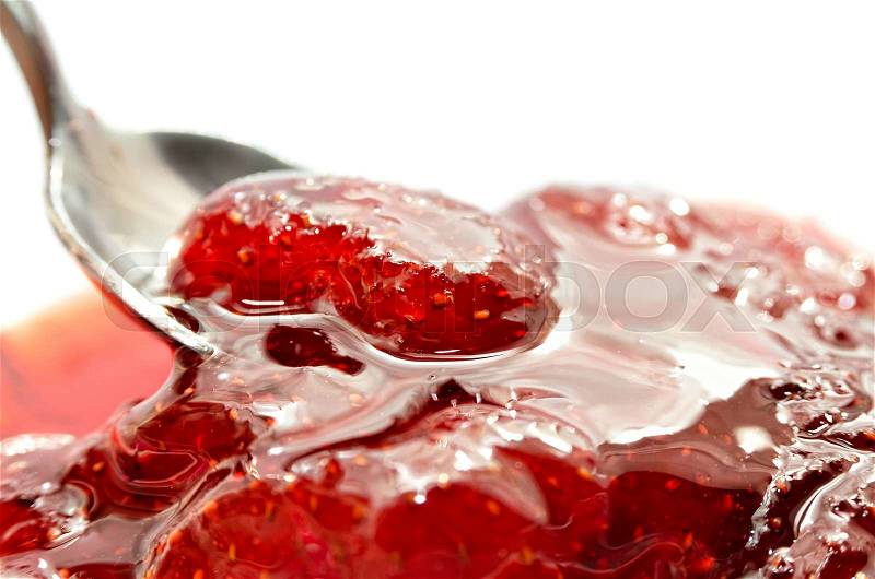 Strawberry jam is stirred with a spoon on a white background. Fruit dessert close up. Confectionery, stock photo