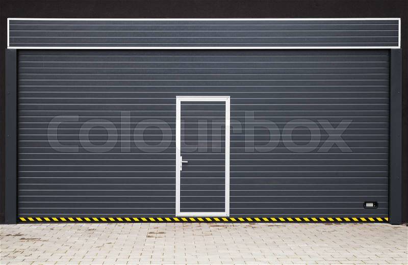 Dark gray modern garage gate with small door in the middle, background photo texture, stock photo