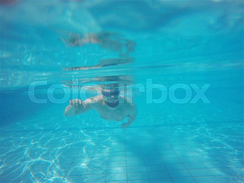 Young beard man with glasses swimming under water in the pool, stock photo
