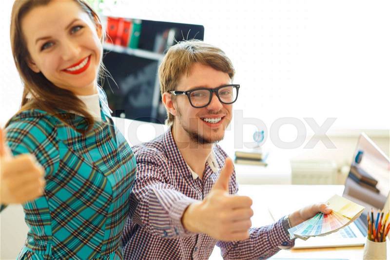 Beautiful young woman and man with thumb up in office - modern business concept, stock photo