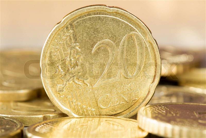 Closeup of a 20 euro cent coin standing between other coins, stock photo