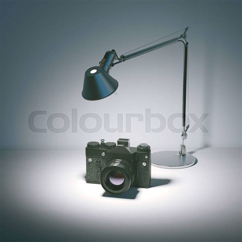 Table lamp illuminates a vintage photo camera, stock photo